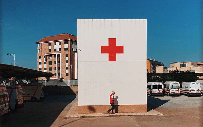 Person walking infront of red cross, Photo by Jon Tyson on Unsplash
